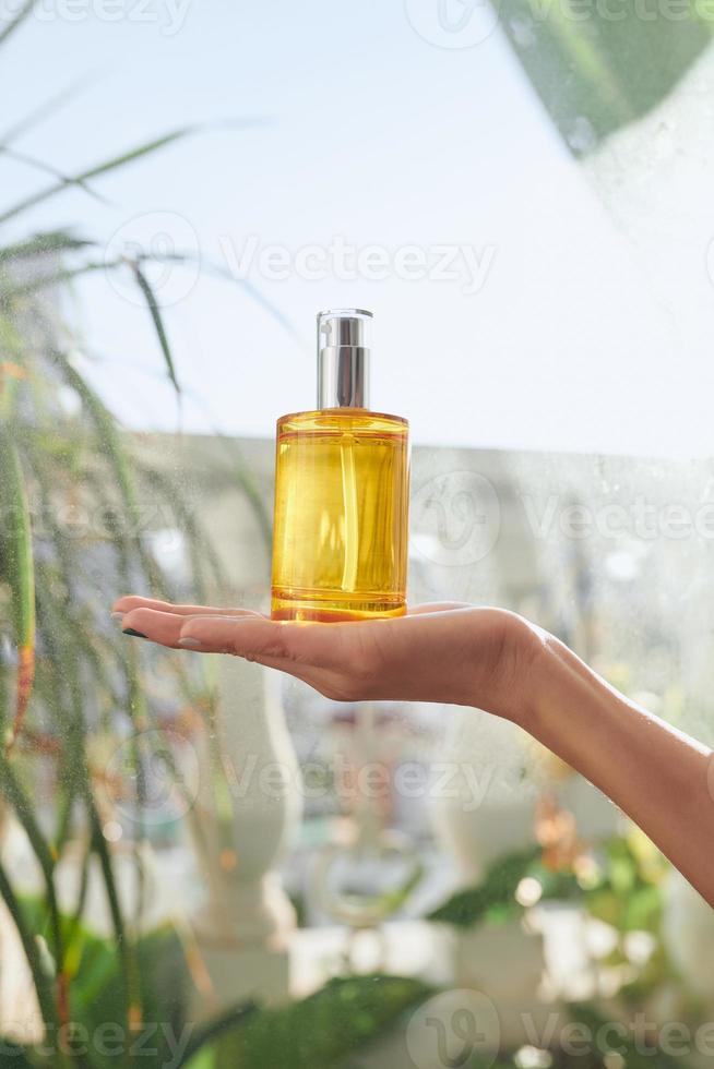 centrarse en la botella de perfume en la mano de la mujer. foto