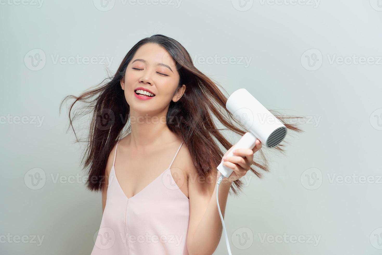 Close up portrait of beautiful young woman drying hairstyle. Cute young lady smiling . photo