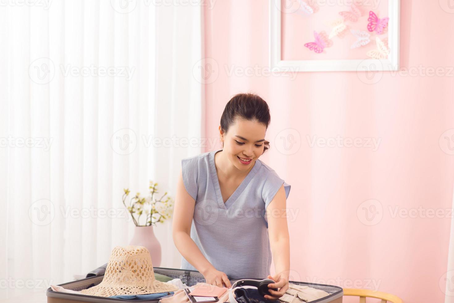 Young woman packing suitcase on bed, closeup photo