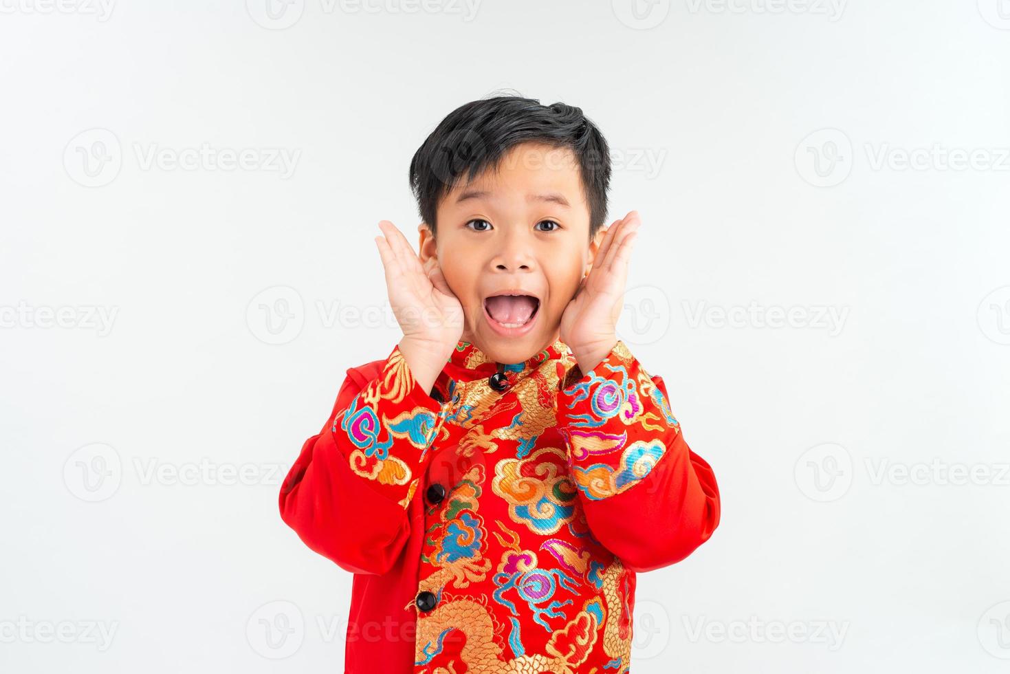 Portrait of a little Asian boy looking extremely surprised with his mouth open and hands on his face photo