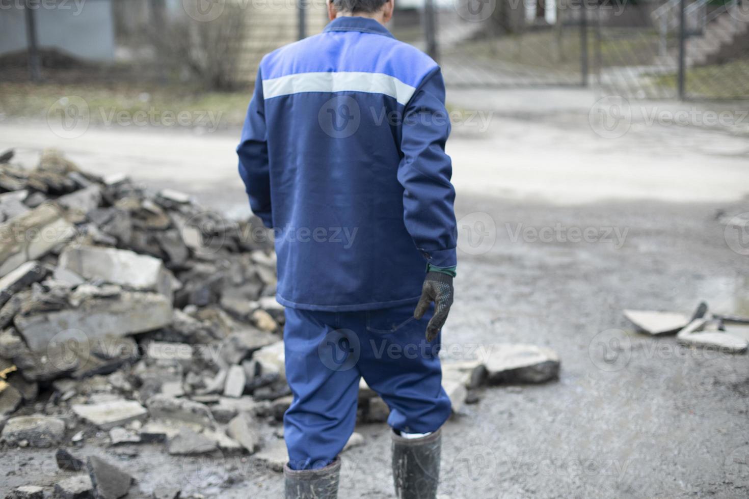 Worker in blue clothes. Road worker removes rocks. photo