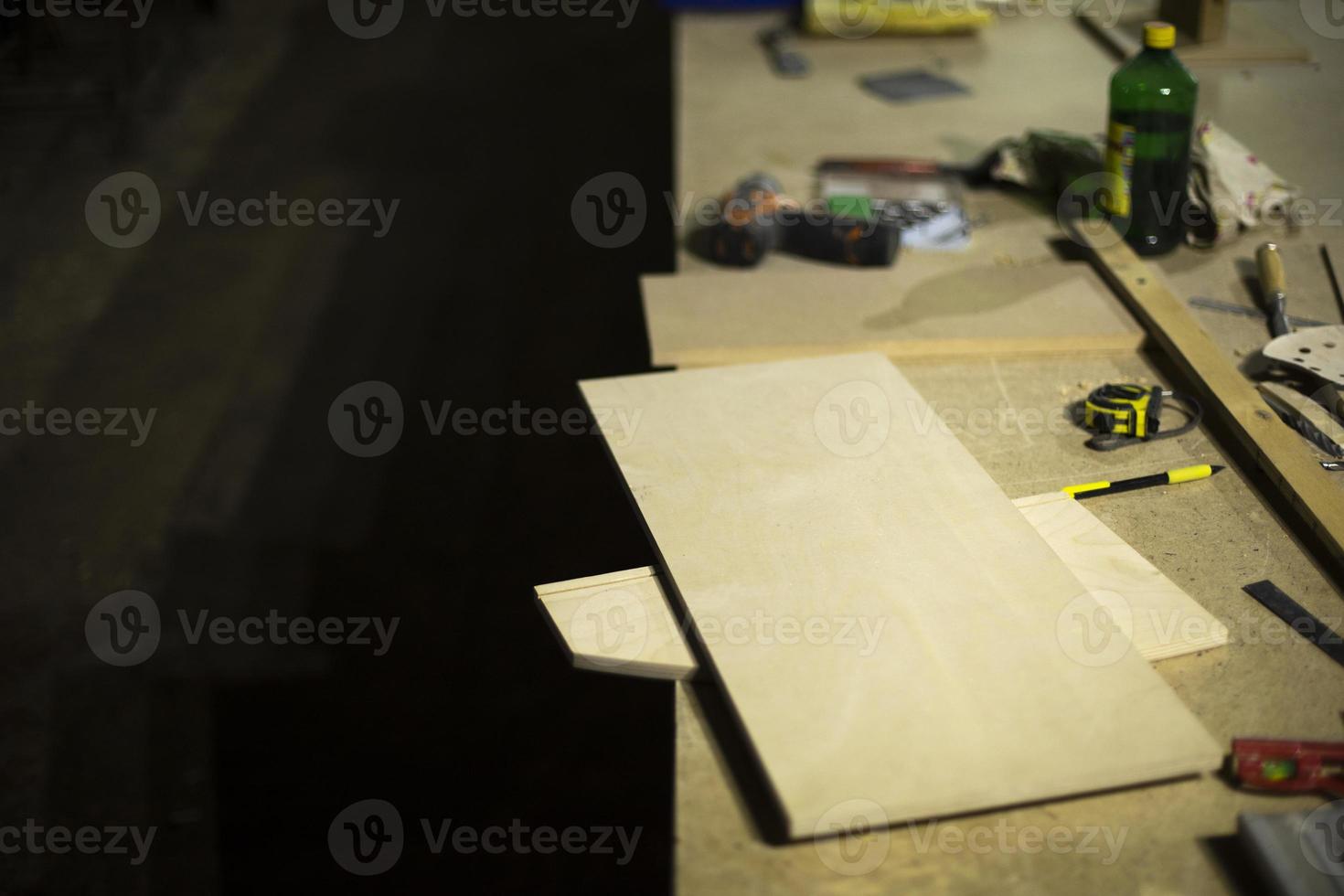Table in wood workshop. Furniture assembler's workplace. Boards lying on table. photo