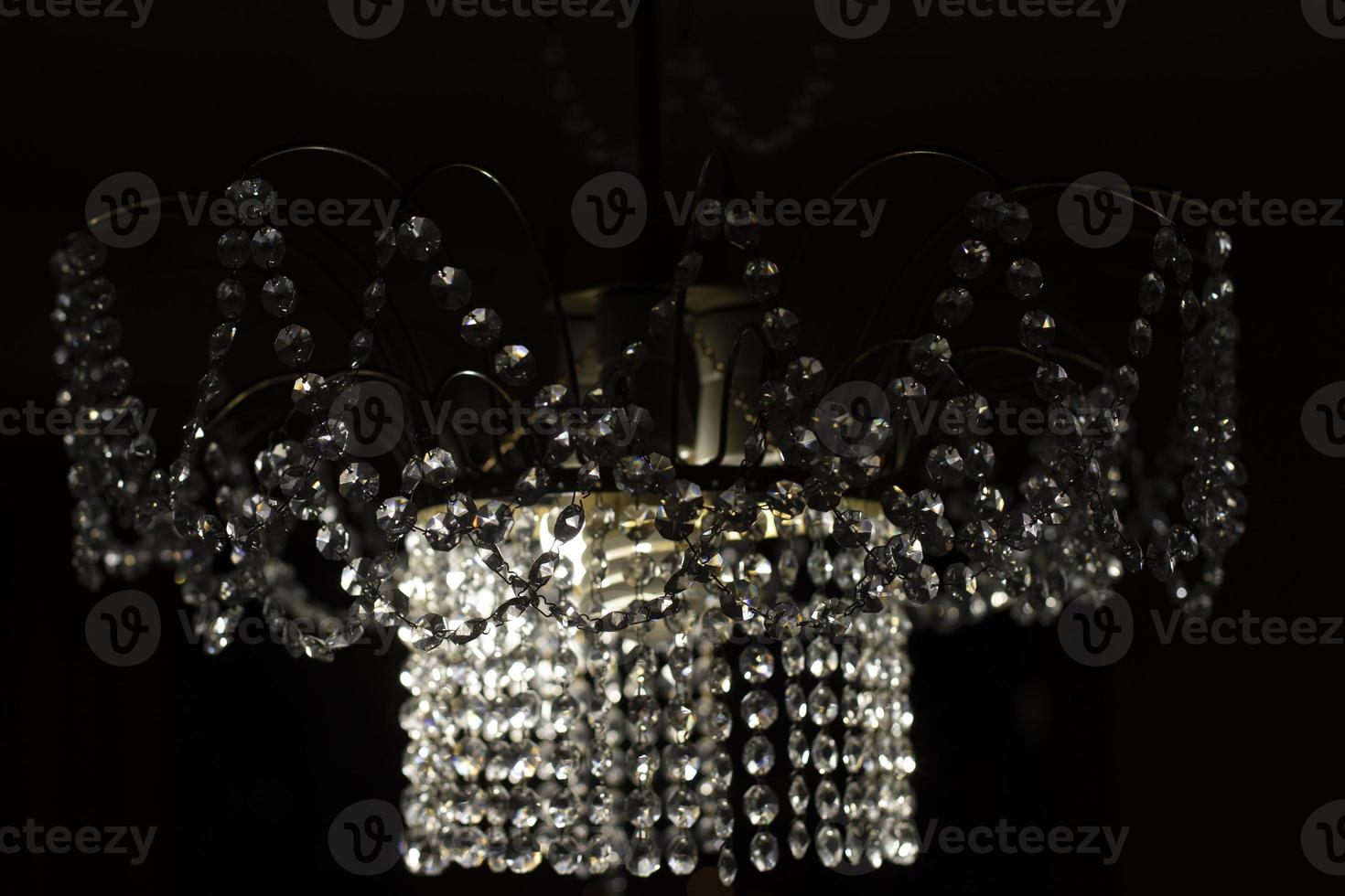 Crystal chandelier made of glass. Chandelier in interior. Light in dark. Reflection of light in glass. photo