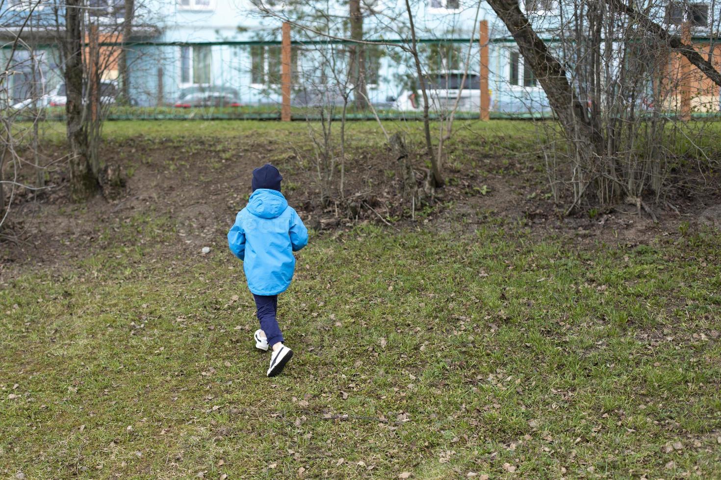 Child runs to fence. Kids got lost in street. Boy hurries home. photo