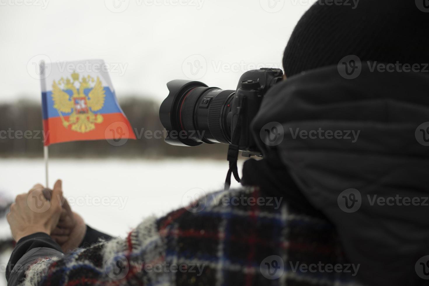 Photographer shoots flag of Russia. Small flag in hand. photo