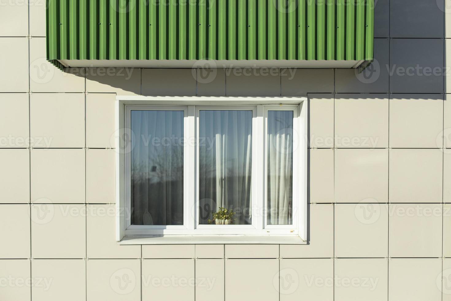 Window in building. White window in wall of house. Green balcony. photo