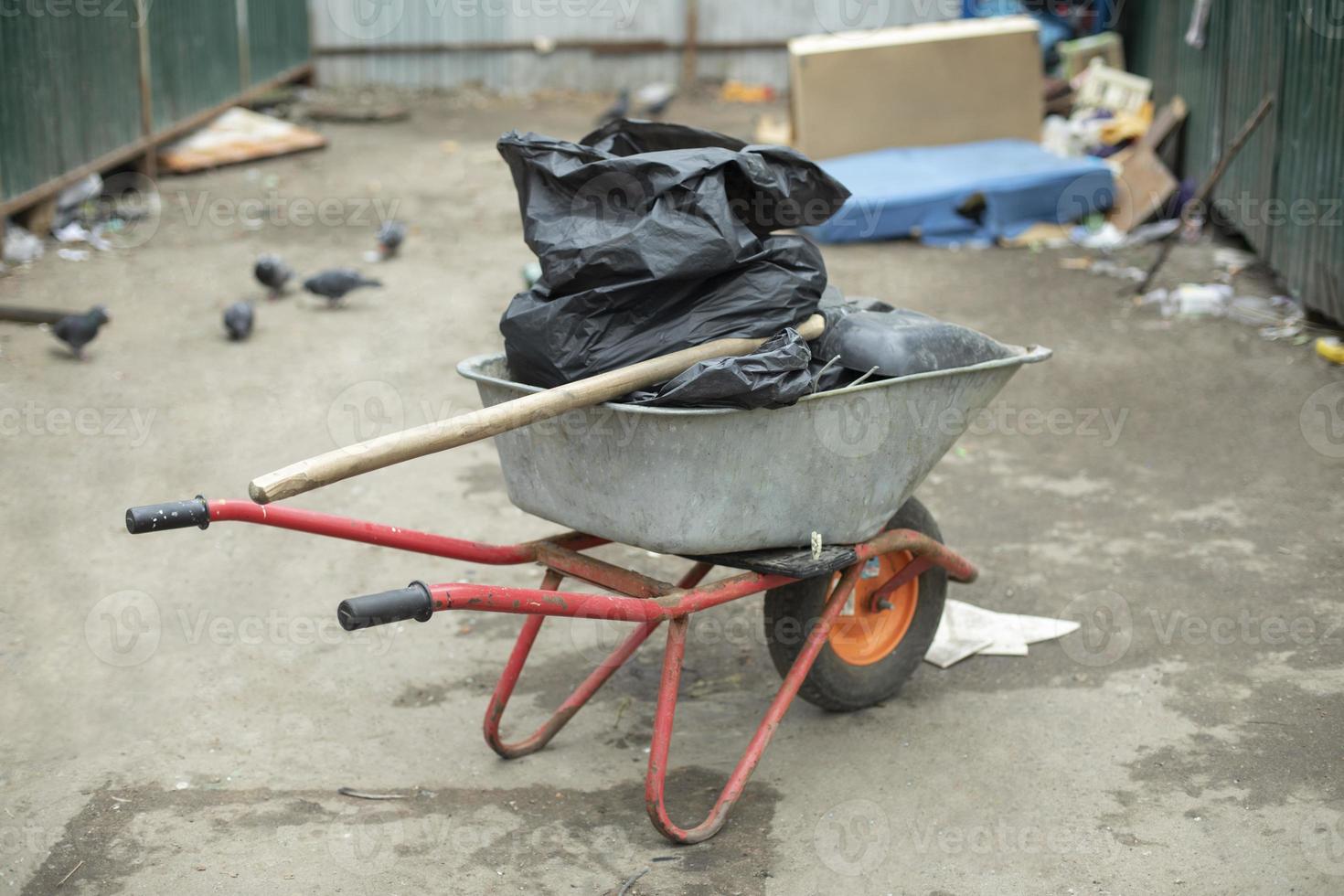Garden cart with black bags inside. Cleaning of territory. Transportation of garbage. photo