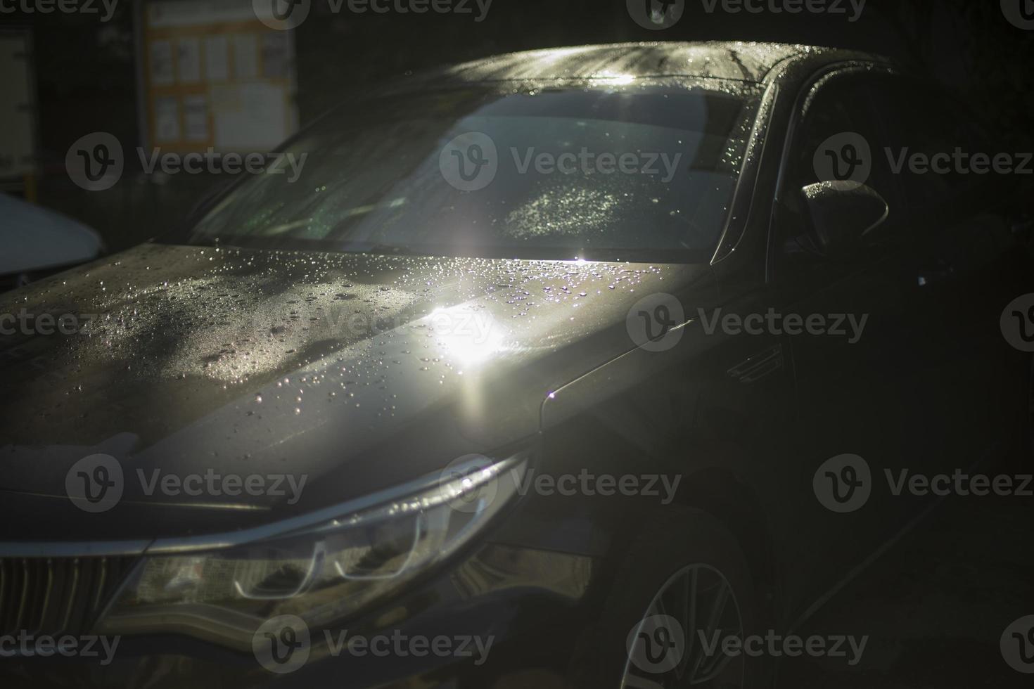 coche en estacionamiento. coche negro al sol. el coche está en gotas. foto