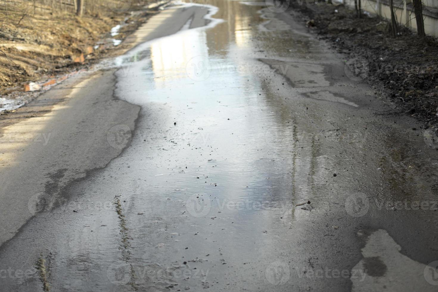 Puddle on asphalt. Wet road. Spilled water on pedestrian zone. photo