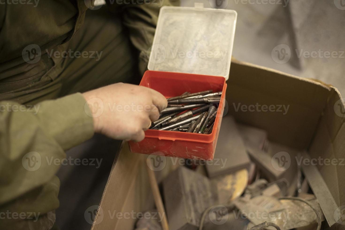 Drill bits in box. Hand holds box of drills. Tools in garage. photo