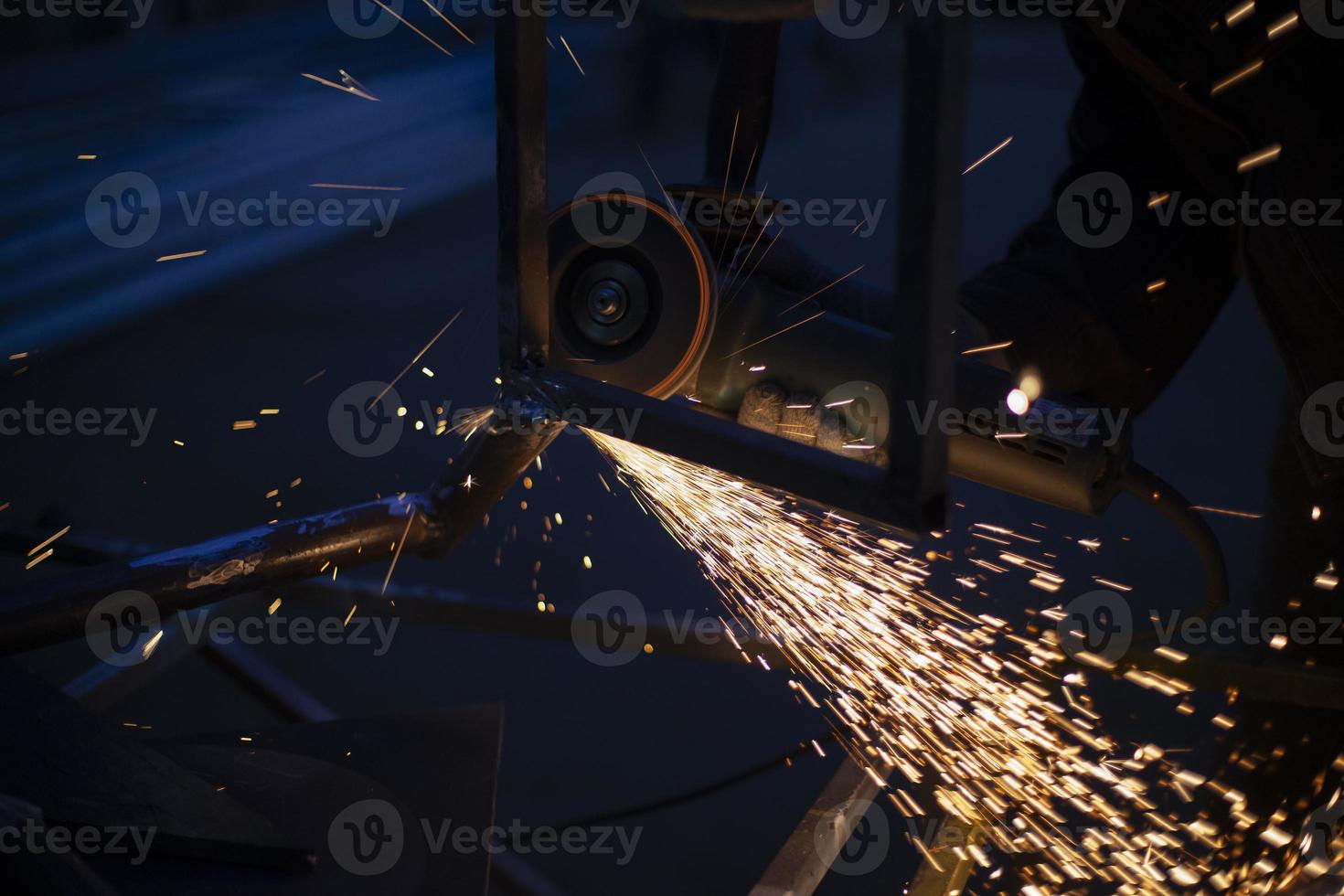 Sparks from grinding metal. Steel processing in workshop. Lights in dark. Production of parts. Cutting became grinder. photo