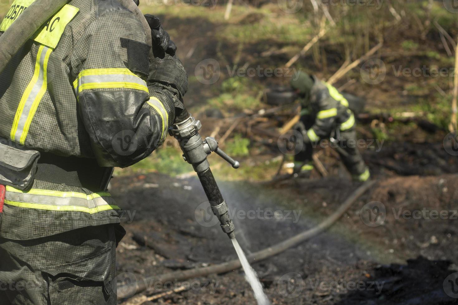 Firefighter pours water from hose. Extinguishing fire in detail. Water from hydrant. photo