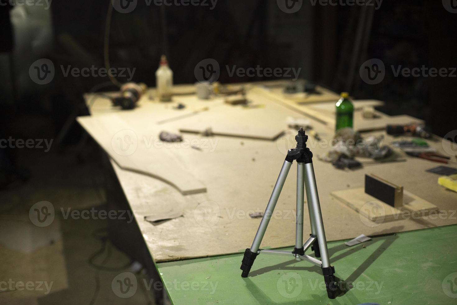 Tripod on table in carpentry workshop. Tool for shooting on camera. photo