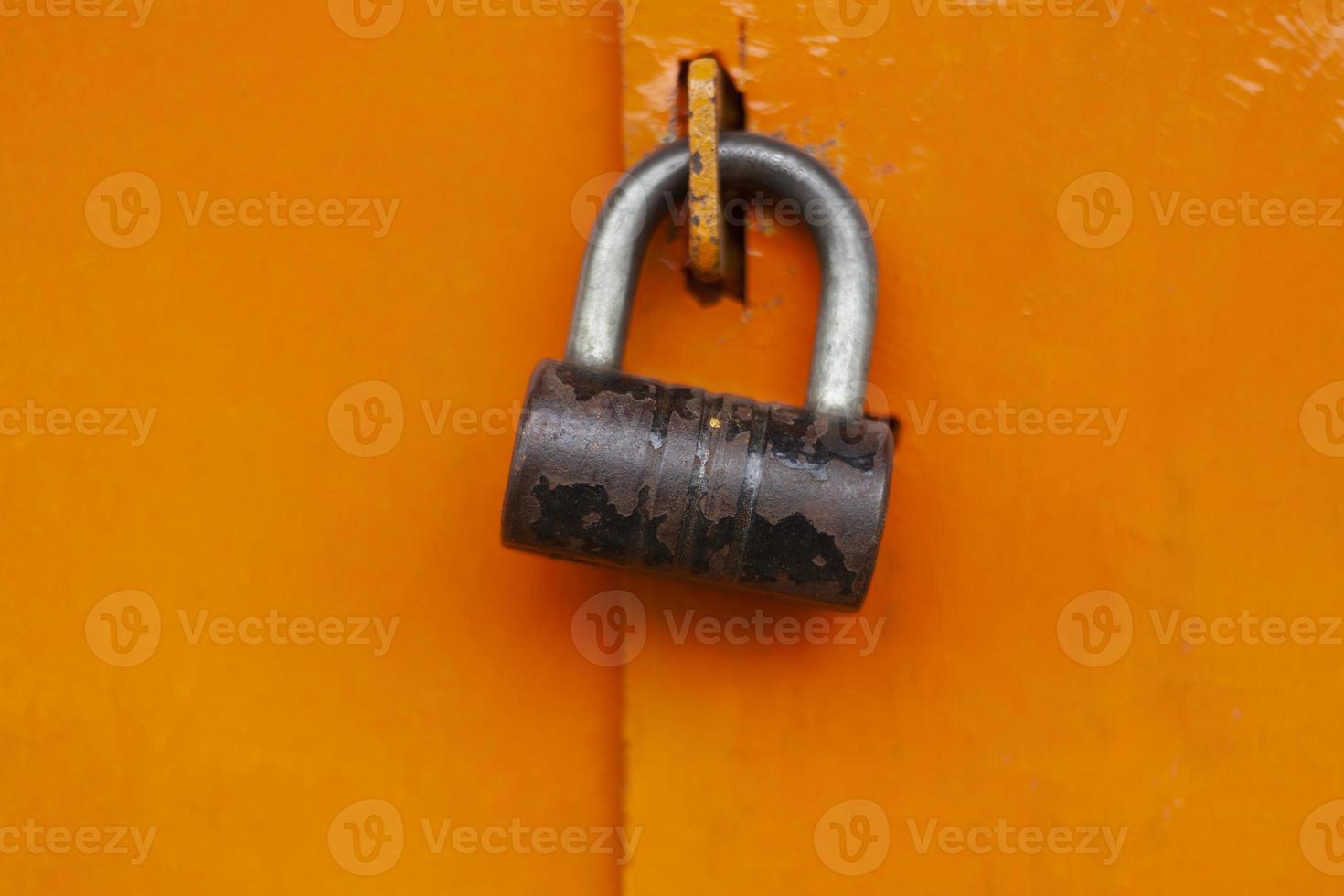 Lock on door. Steel lock on orange gate. Closed door. photo