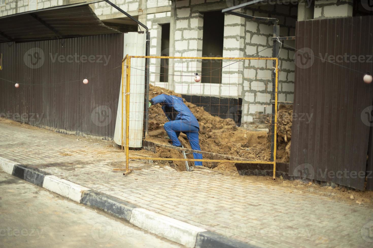 Worker near fence. Builder repairs house. Details of construction of house. photo