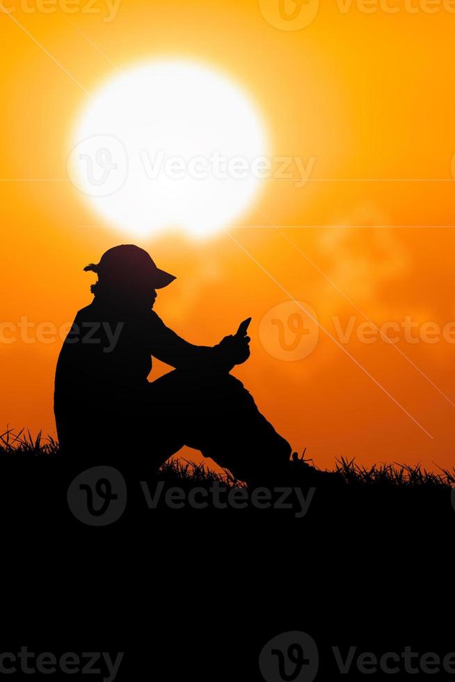 Silhouette of an unemployed man sitting and watching phone to find work photo