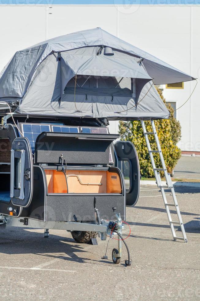 Camper, a small mobile home on wheels as a trailer to a car in a parking lot. photo