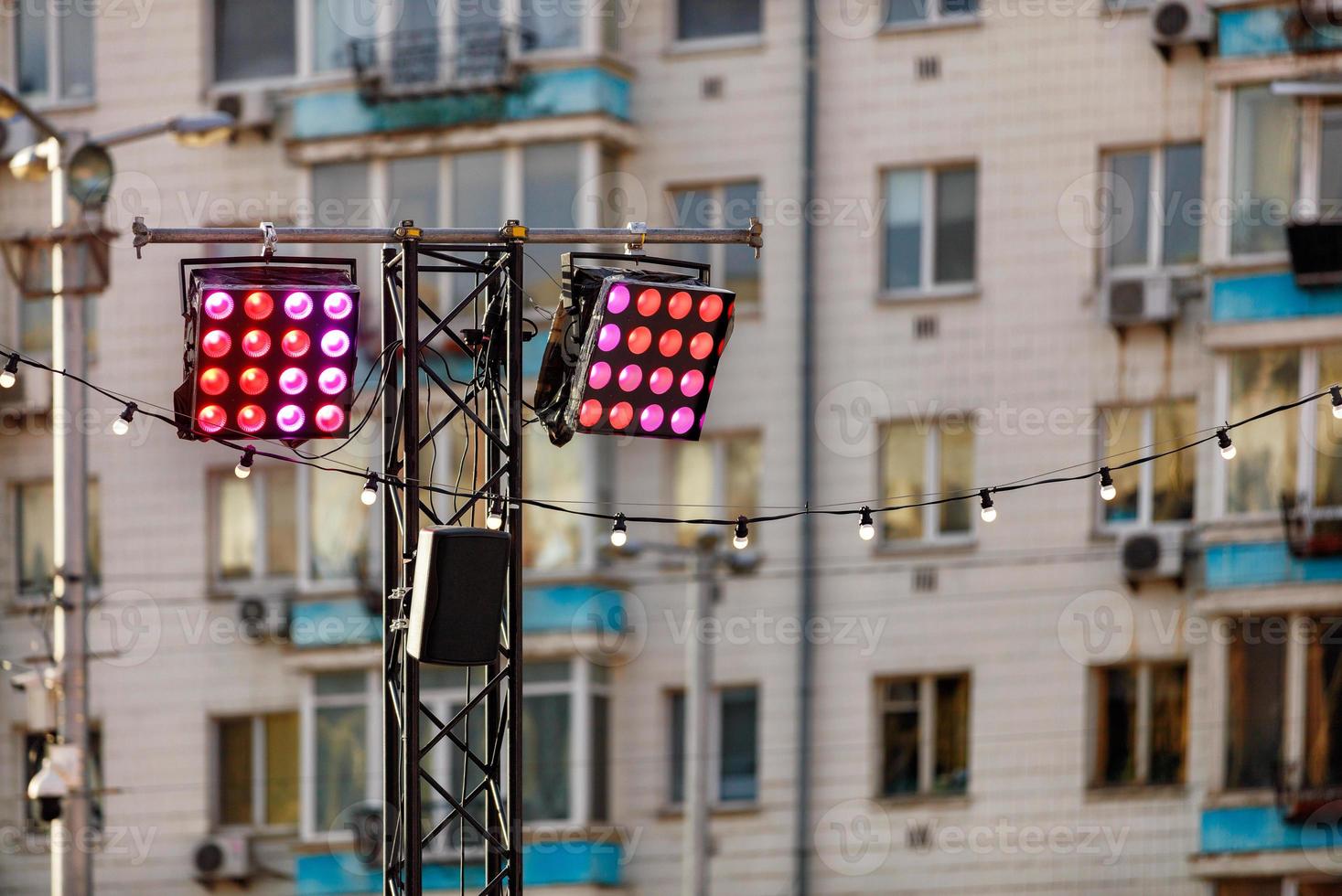 Street lighting with red and pink spotlights on the background of an apartment building in blur. photo