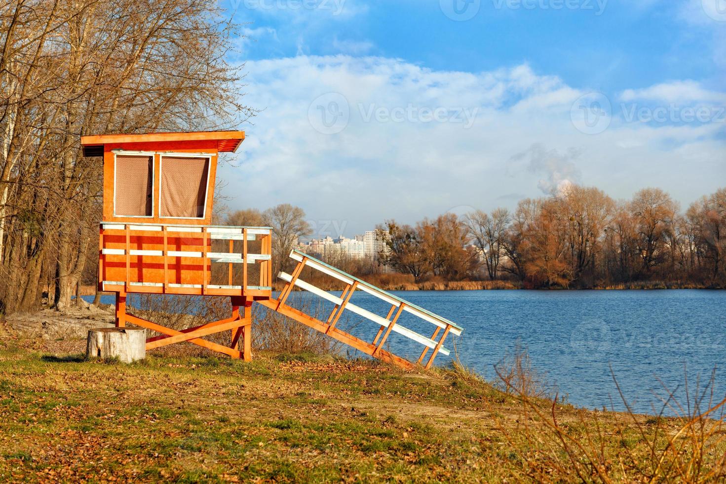 Lifeguard tower on the river bank in the golden rays of the setting autumn sun. photo