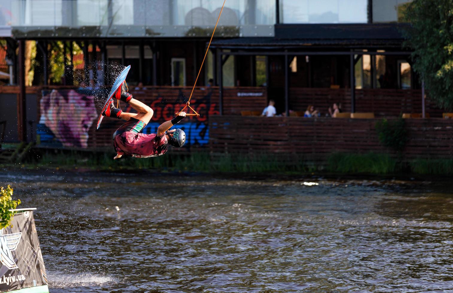 A dizzying trick of a wakeboarder over the surface of the water on a dark background. 06.19.1922. Kyiv. Ukraine. photo