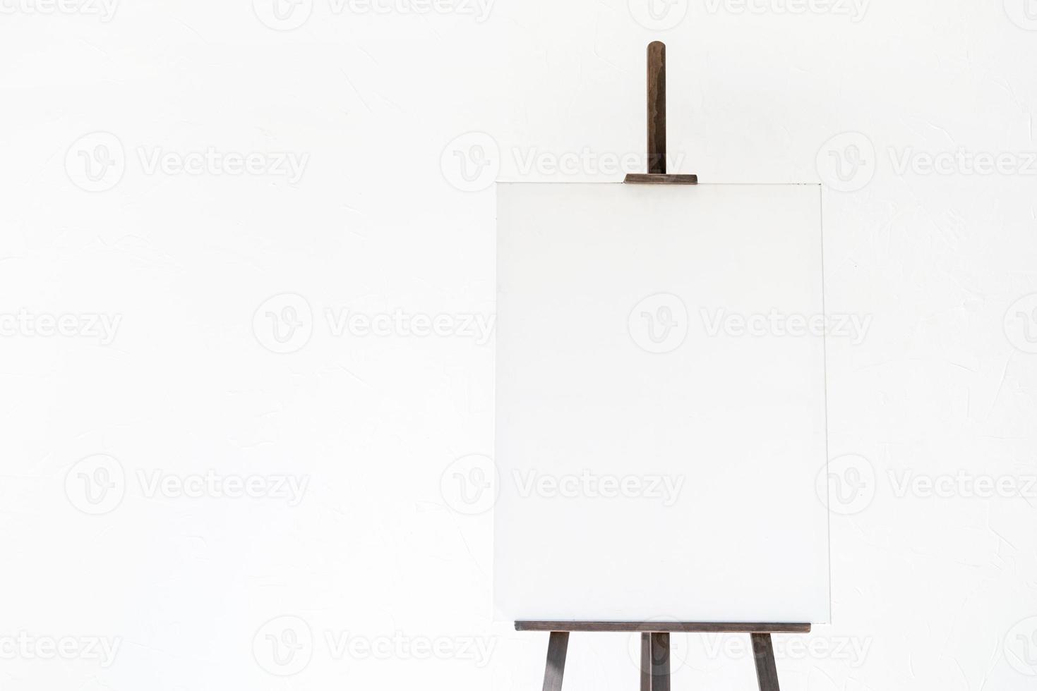 Wooden easel with blank canvas on light background for mockup design photo
