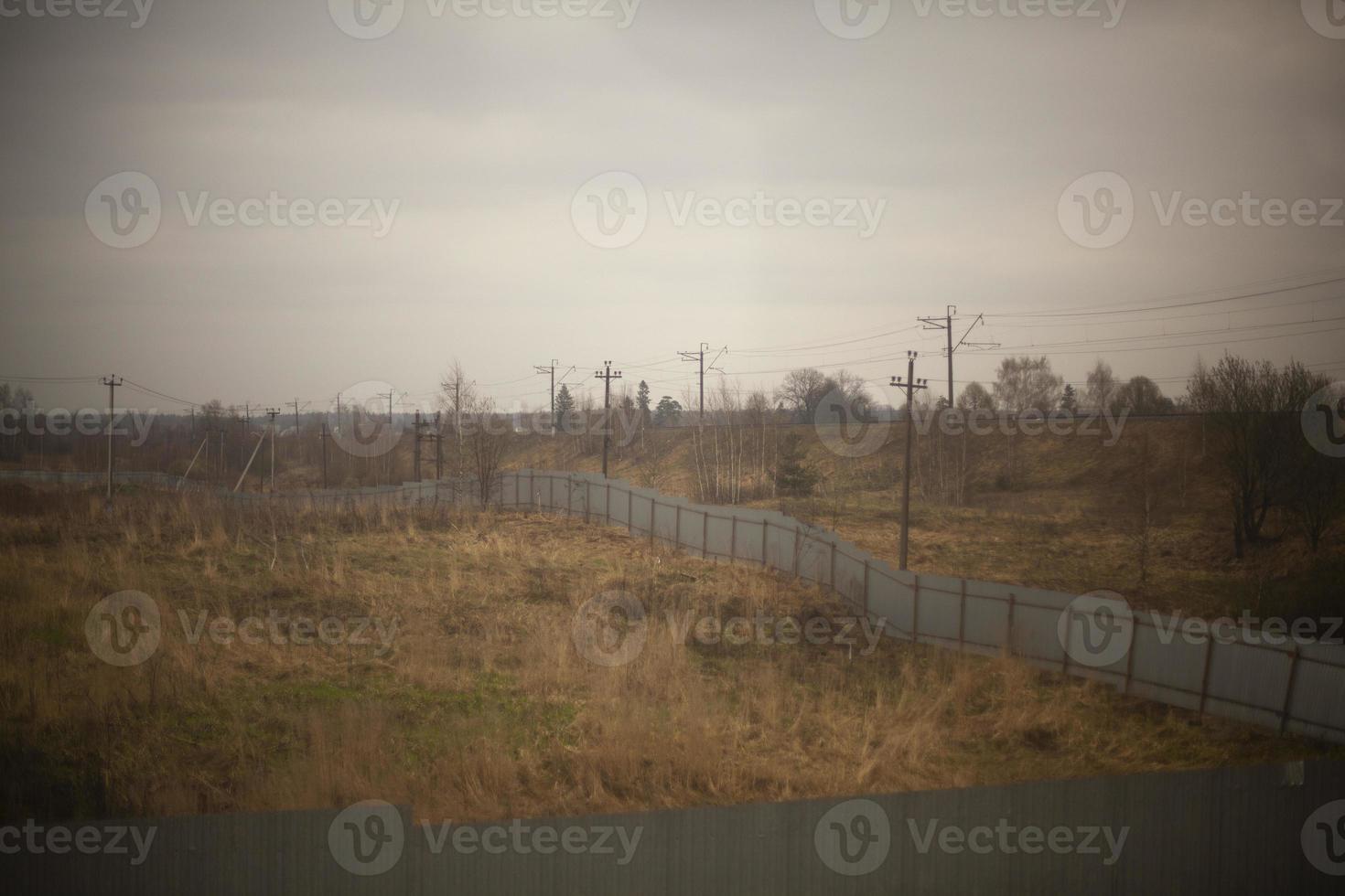 Fence in field. Fenced empty field. Steel fence is long. photo