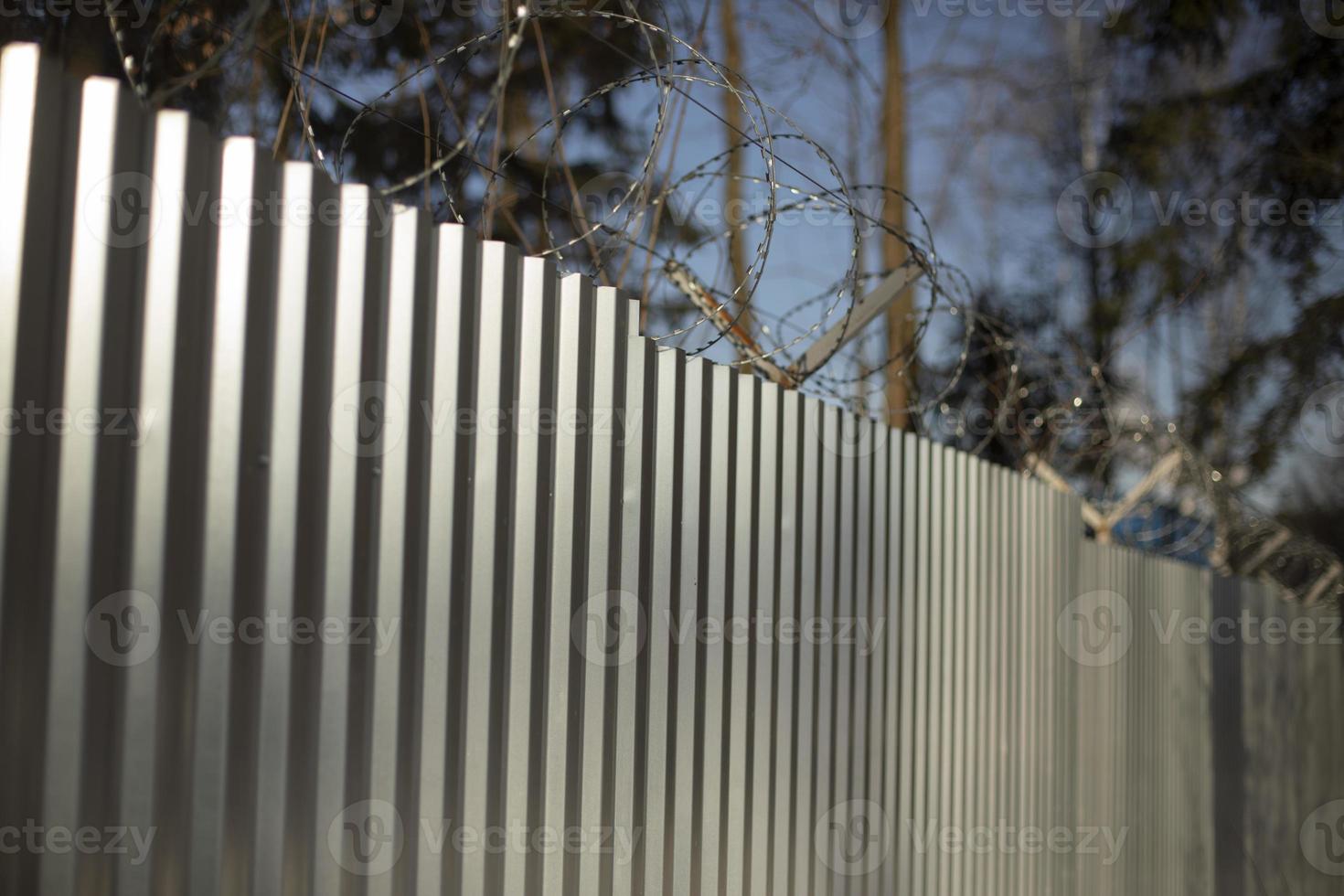 Steel fence with barbed wire. Fencing of territory. Industrial zone. Stainless steel. photo