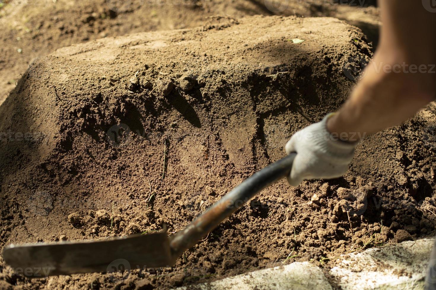 Undertaker strikes grave. Shovel and earth. Man is digging ground. Sand ramming. photo