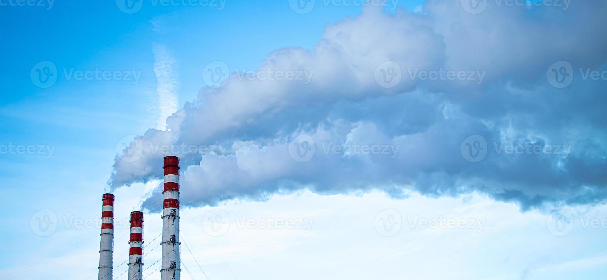 Air pollution. Smoking chimneys against blue sky. photo