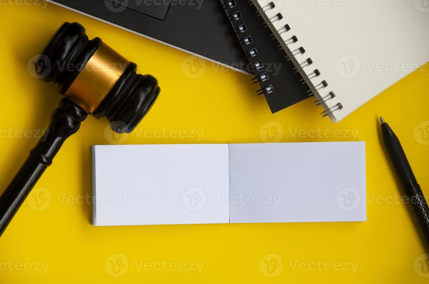 Top view of blank paper note with gavel, laptop and note book on yellow background. Copy space photo