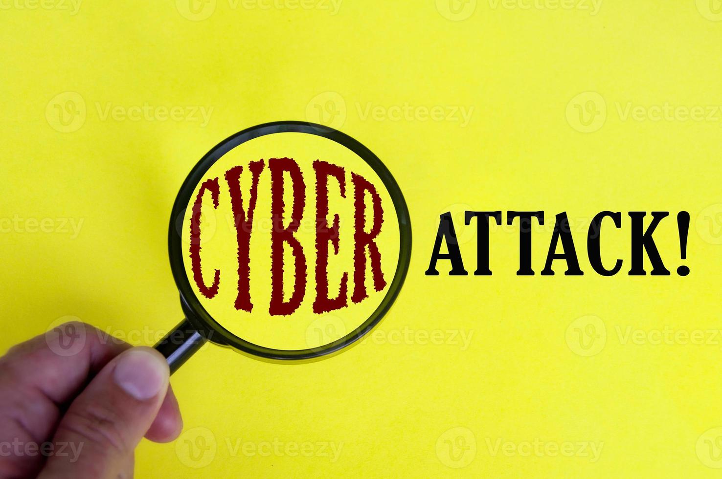 Cyber attack text on yellow cover with hand holding magnifying glass. Internet security concept photo