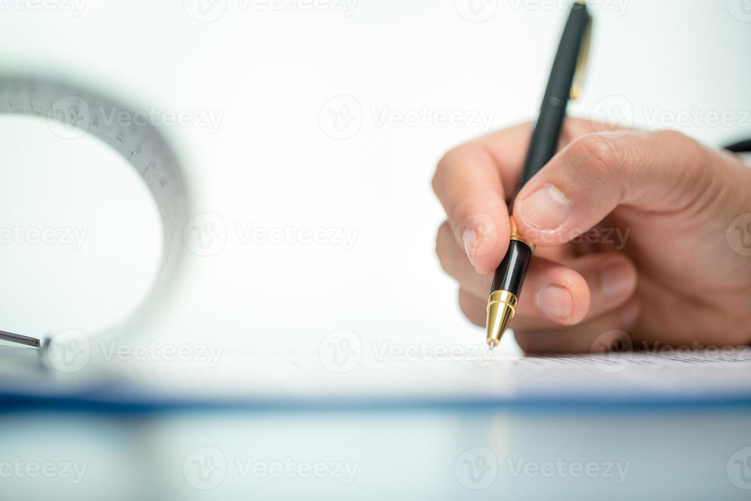 Workplace closeup person professional businesswoman sitting at desk hold pen signing or signature contract paper. Employee woman writing agreement document on paperwork form corporate at work office photo