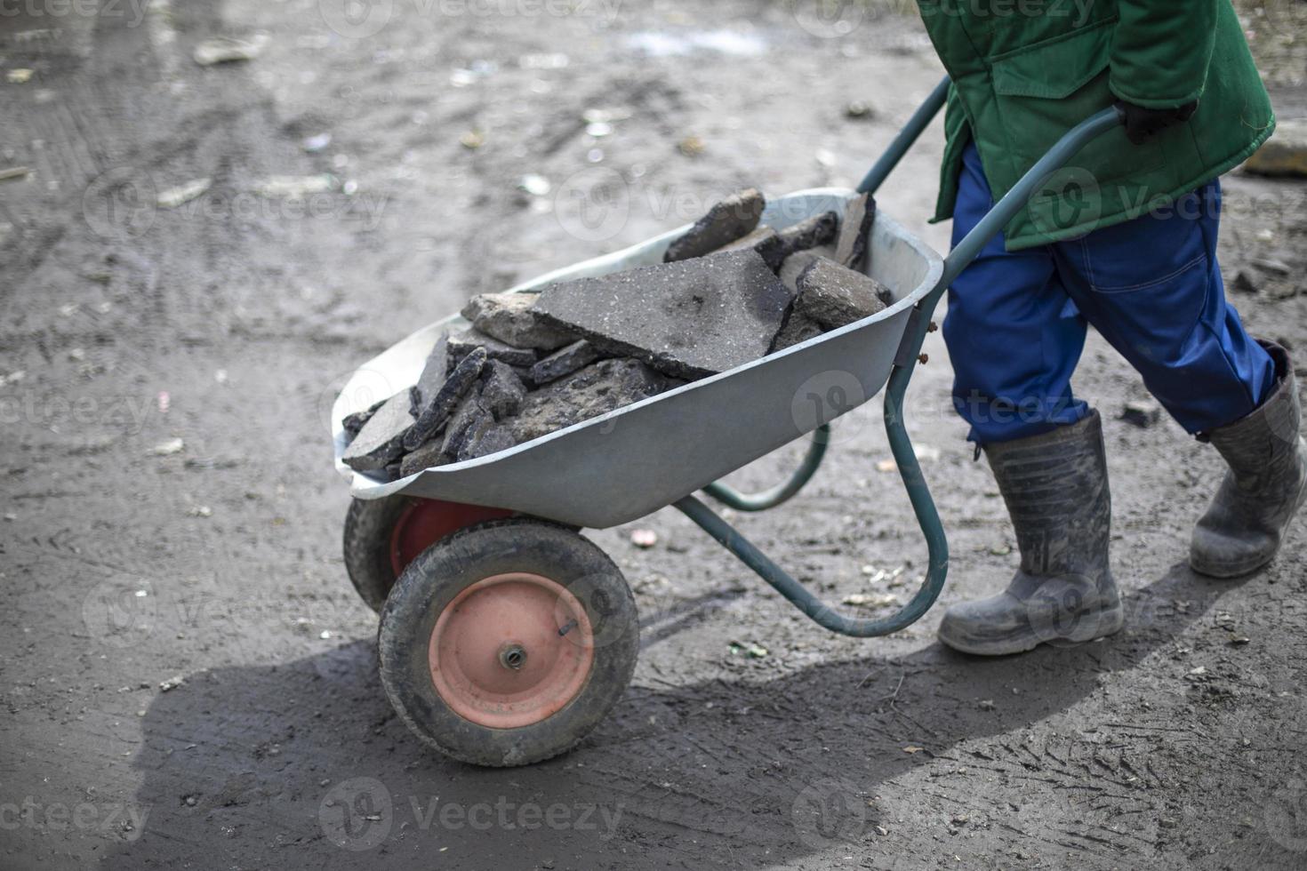 el constructor quita la piedra rota. el hombre lleva adoquines en carro. foto