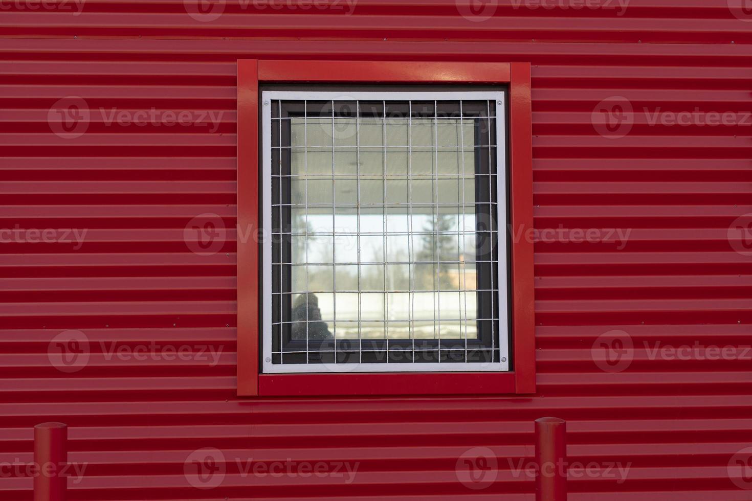 Window in red wall. Window with grille. Details of building. photo