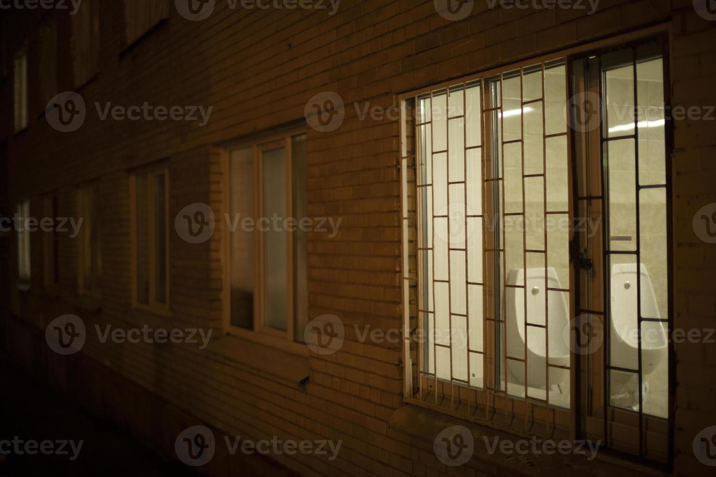 Window in building in evening. Grille on window at night. photo