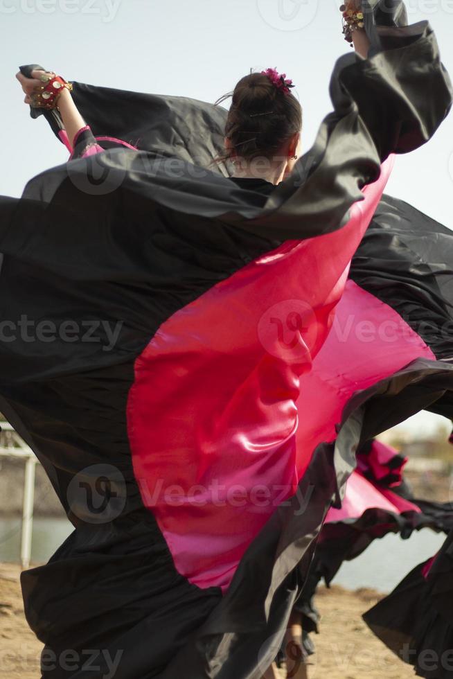 Gypsy dances in bright dresses. Girls dance on street Spanish dance. Bright fabric. photo