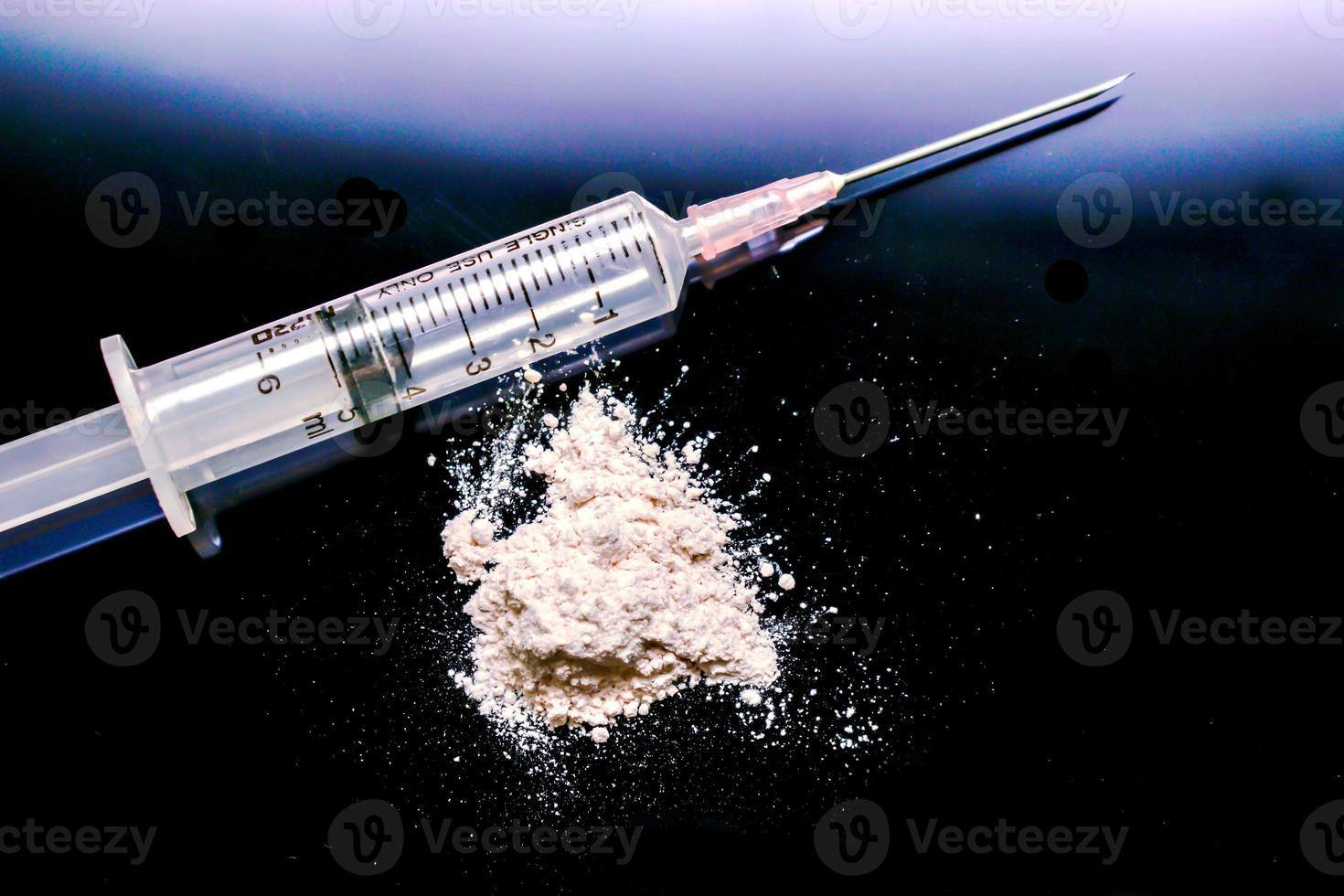 Plastic syringe put in a medical needle and white powder isolate on black background. Suppose to heroin or narcotic addiction. photo