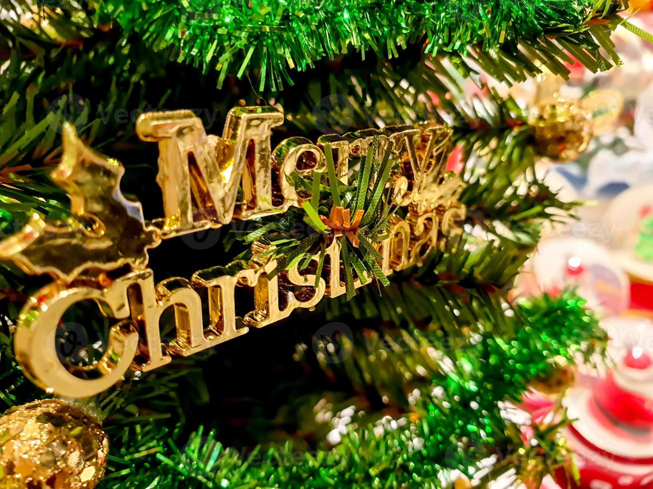 Golden wording of Christmas decorated on pine tree on Christmas day with blurry of Christmas object background . photo