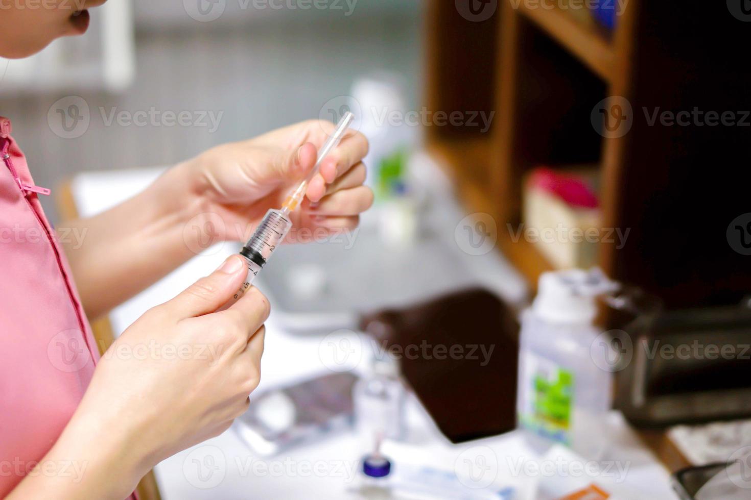 A picture of nurse hands holding a plastic syringe for preparation an injection vaccine for the patient. photo
