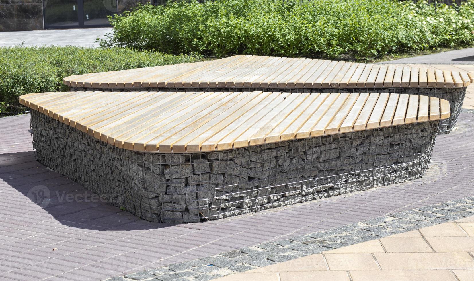 Wooden benches from gabion baskets with stones inside. Wood mounted on gabions. Benches of modern design. There is a recreation area. Detail of a low gabion wall with a wooden top. photo