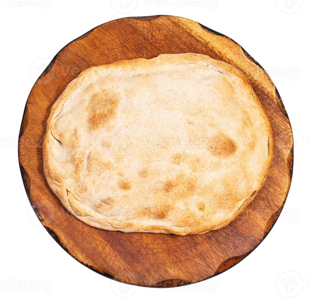 top view of closed flat pie on wooden board photo