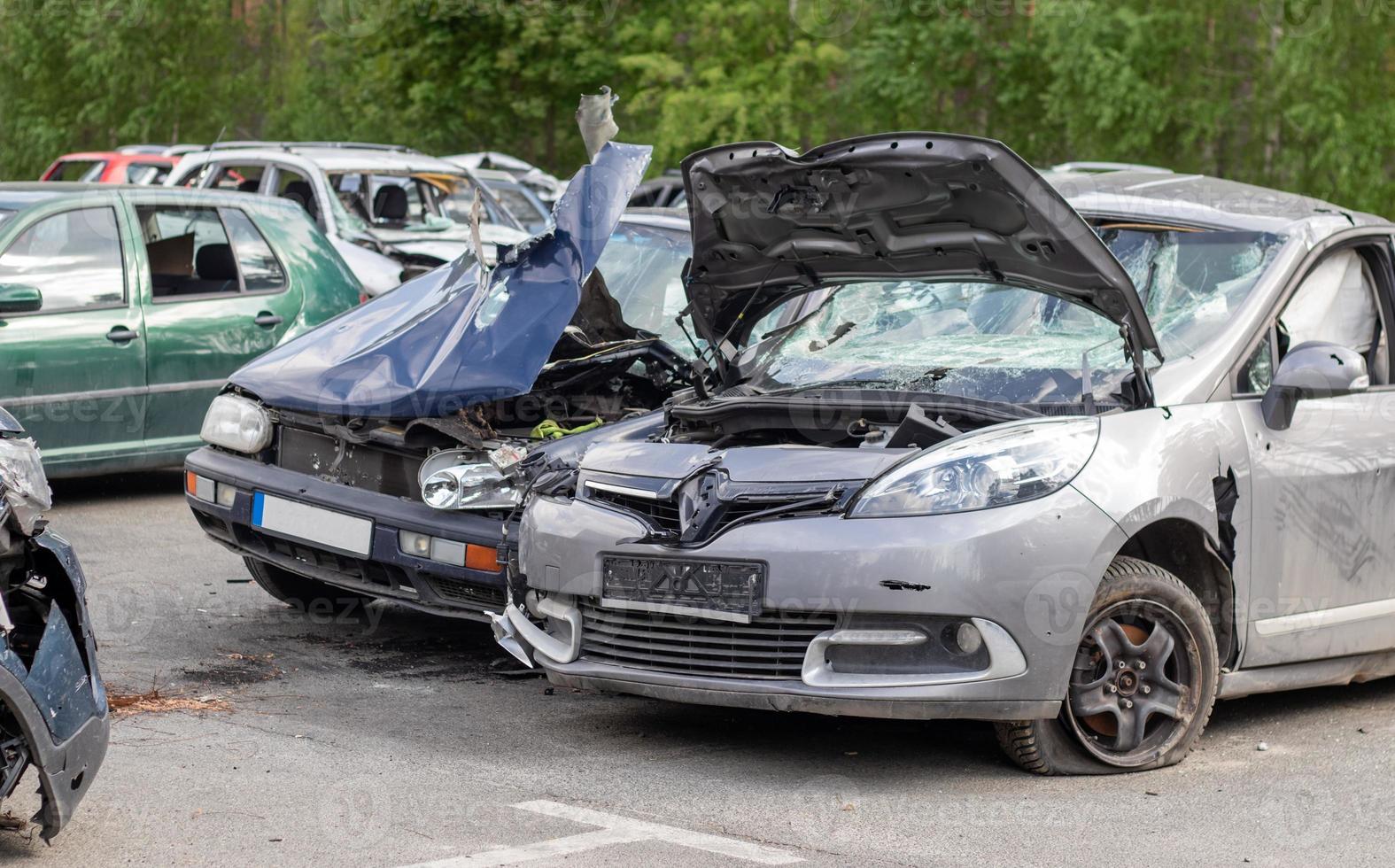 Broken car after a traffic accident in the parking lot of a repair station. Car body damage workshop outdoors. Sale of insurance cars. Accident on the street, car after a collision in the city. photo