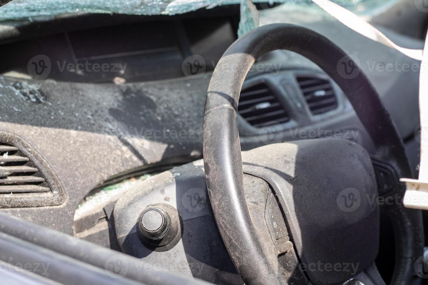 Close-up of the steering wheel of a car after an accident. The driver's airbags did not deploy. Soft focus. Broken windshield with steering wheel. Vehicle interior. Black dashboard and steering wheel. photo