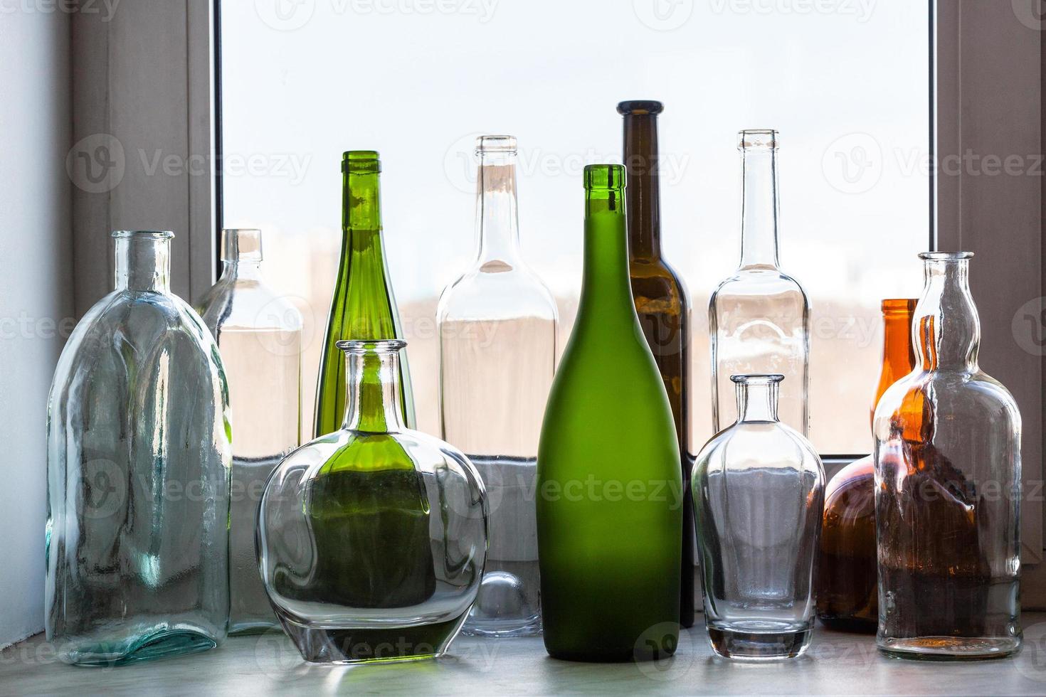 varias botellas vacías en el alféizar de la ventana de casa foto