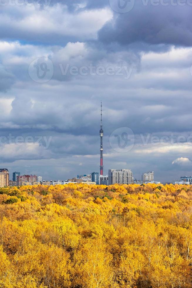 gray rainy clouds over lush yellow forest and city photo