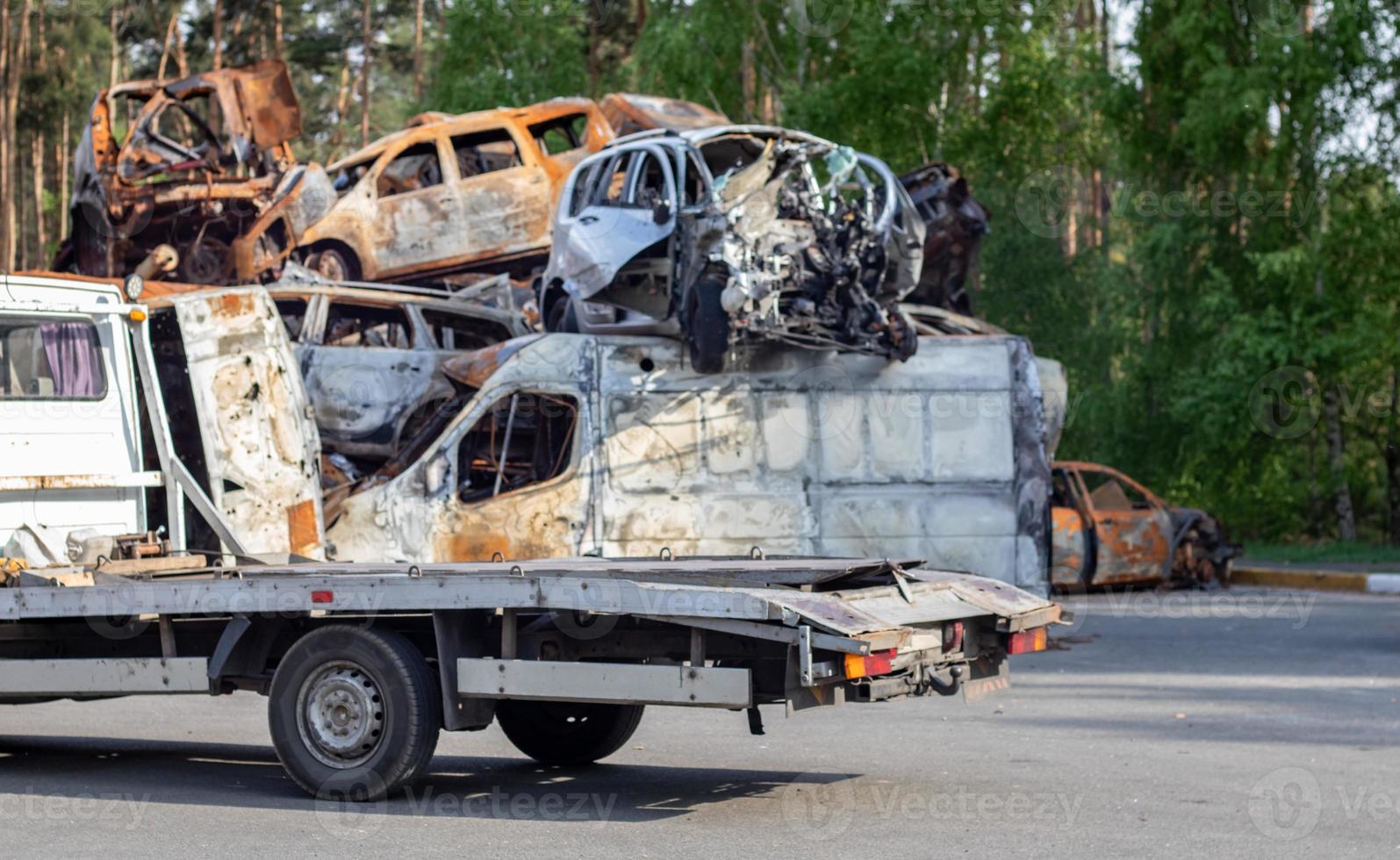 Lots of old cars ready for recycling. Car removal by tow truck. Damaged cars are waiting in a junkyard to be recycled or used for parts. The process of car recycling at a car junkyard. photo