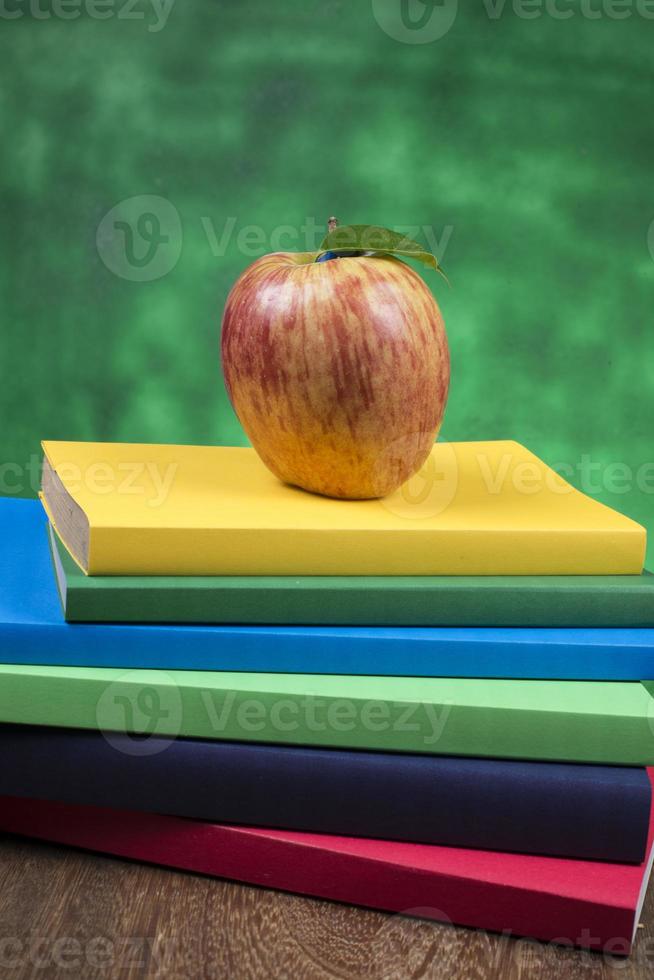 Apple fruit on top of a book stack, on the back of school classes. photo