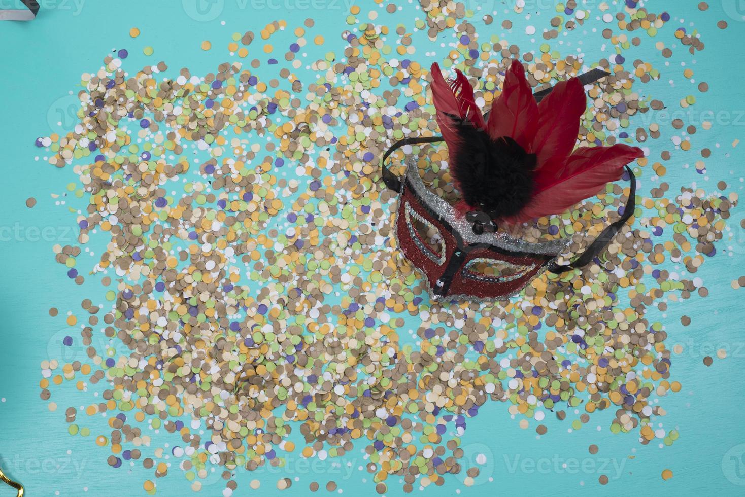 confetti spread on blue background with a female carnival mask photo