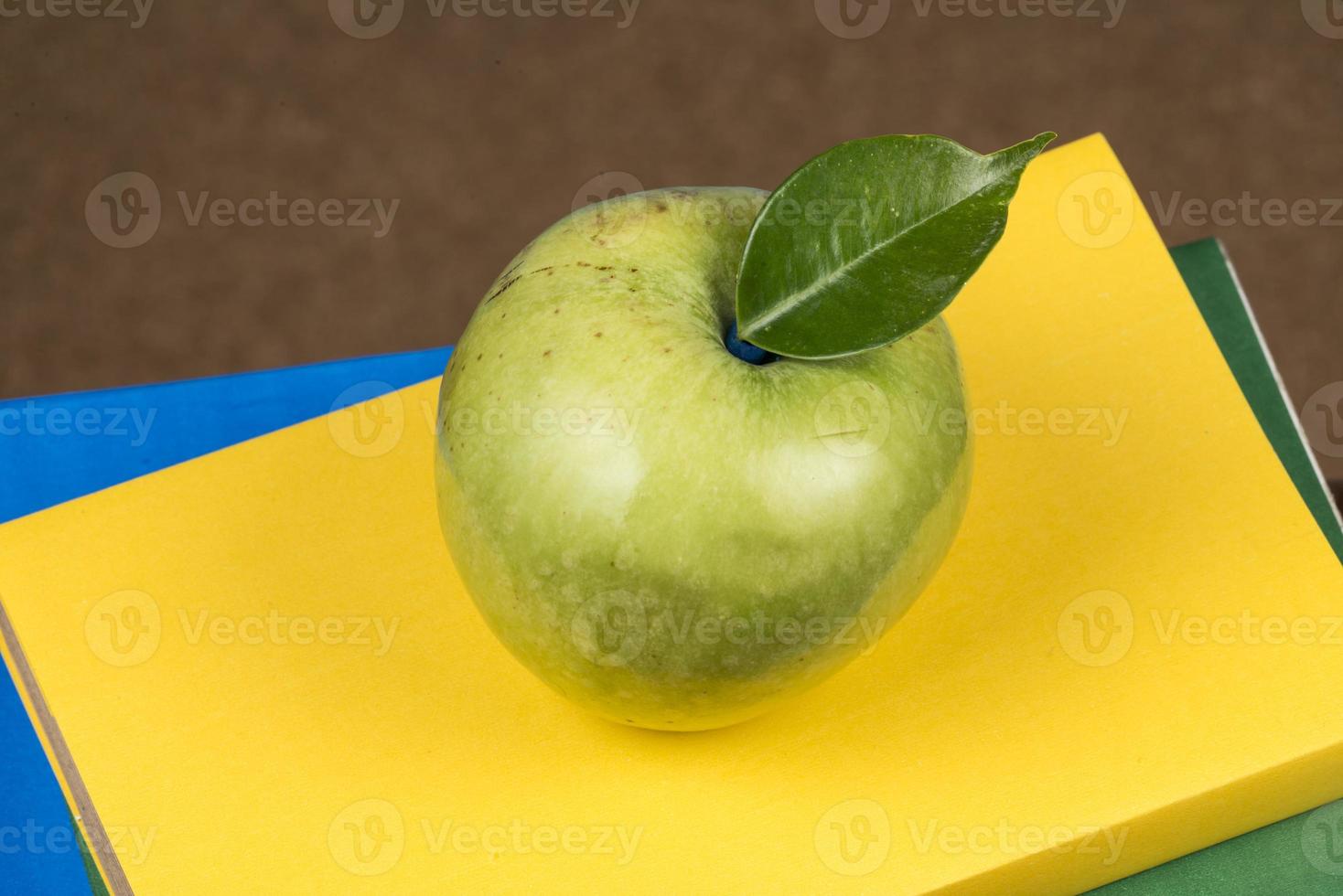 fruta de manzana encima de una pila de libros, en la parte posterior de las clases escolares. foto