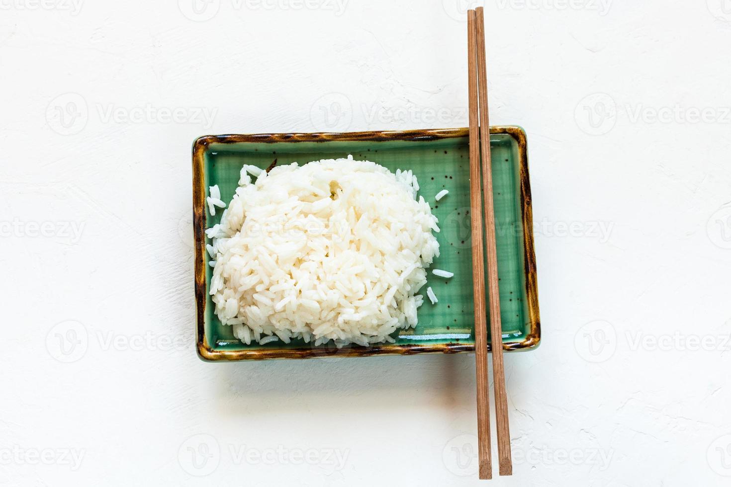 boiled rice and chopsticks on green plate on white photo